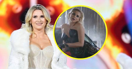 Kajra w lateksowym kostiumie wygina się na masce samochodu. Ostra stylizacja