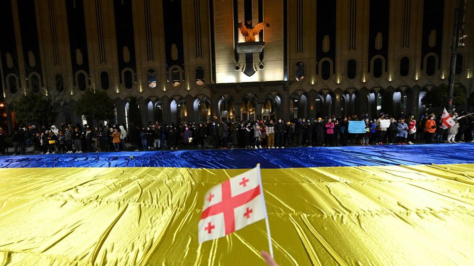 ?wiatowe demonstracje wsparcia dla UkrainyA demonstrator waves a flag of Georgia near a giant Ukrainian flag during a rally in support of Ukraine in Tbilisi, on the 12th day of the Russian invasion of Ukraine, on March 7, 2022. - EU nations agreed on March 7, 2022 to start the lengthy process of examining membership bids submitted by Ukraine, Georgia and Moldova in the wake of Russia's invasion of its pro-Western neighbour, diplomats said. (Photo by Vano SHLAMOV / AFP)VANO SHLAMOV