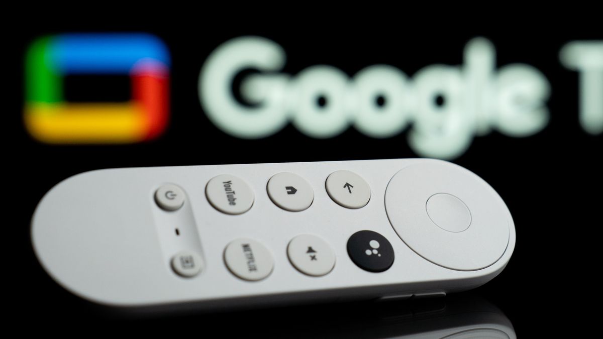A Google Chromecast controller is in front of a TV with the Google TV logo. (Photo by Nikos Pekiaridis/NurPhoto via Getty Images)