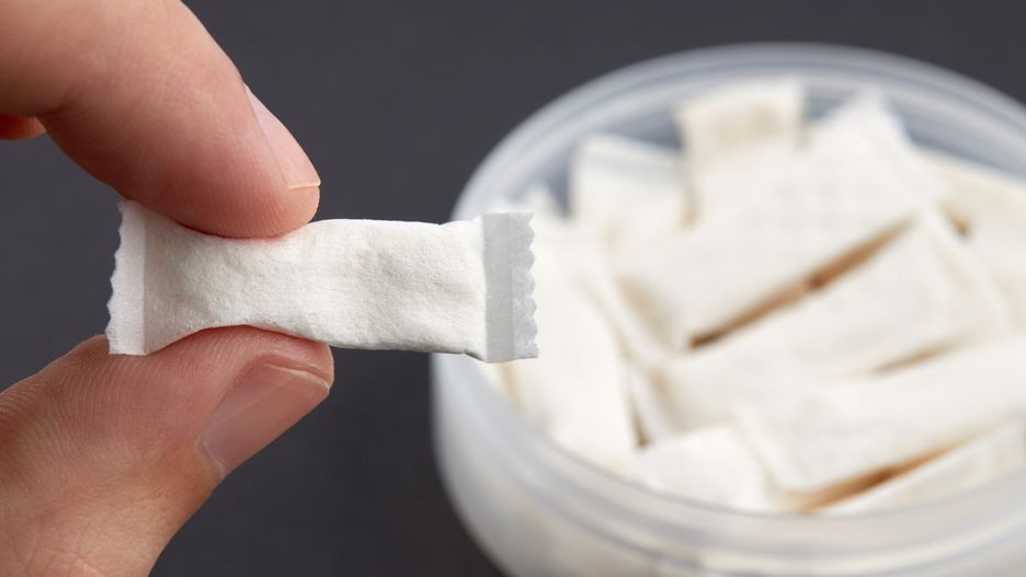 caucasian person holds snus tobacco pouch over black background. copy space. alternative chewing nicotine smoking.