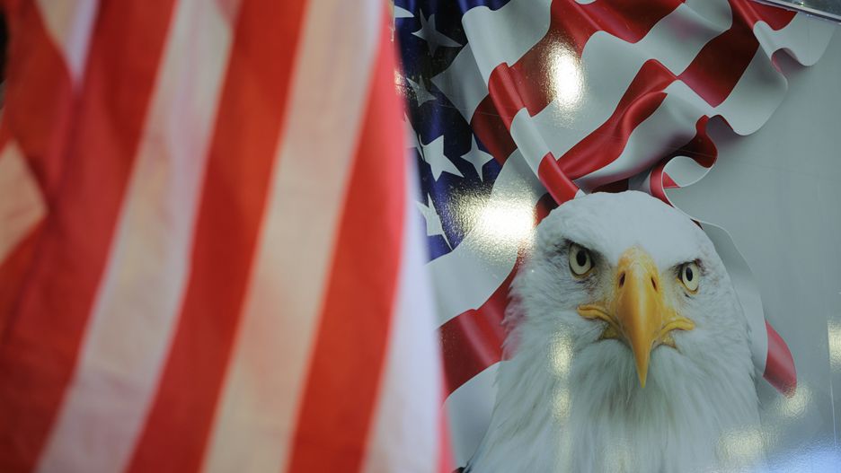 OXON HILL, MARYLAND - FEBRUARY 21: An attendee waves an American flag next to a truck with a bald eagle illustration during the Conservative Political Action Conference (CPAC) at the Gaylord National Resort & Convention Center on February 21, 2025 in Oxon Hill, Maryland. The annual four-day gathering brings together conservative U.S. lawmakers, international leaders, media personalities and businessmen to discuss and champion conservative ideas. (Photo by Kayla Bartkowski/Getty Images)