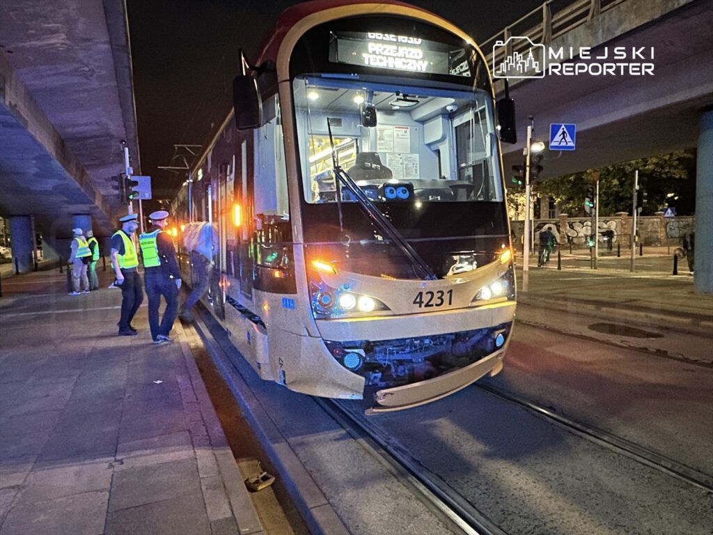 Tramwaj z numerem 4231 zatrzymany na przystanku, obok grupy funkcjonariuszy w odblaskowych kamizelkach.