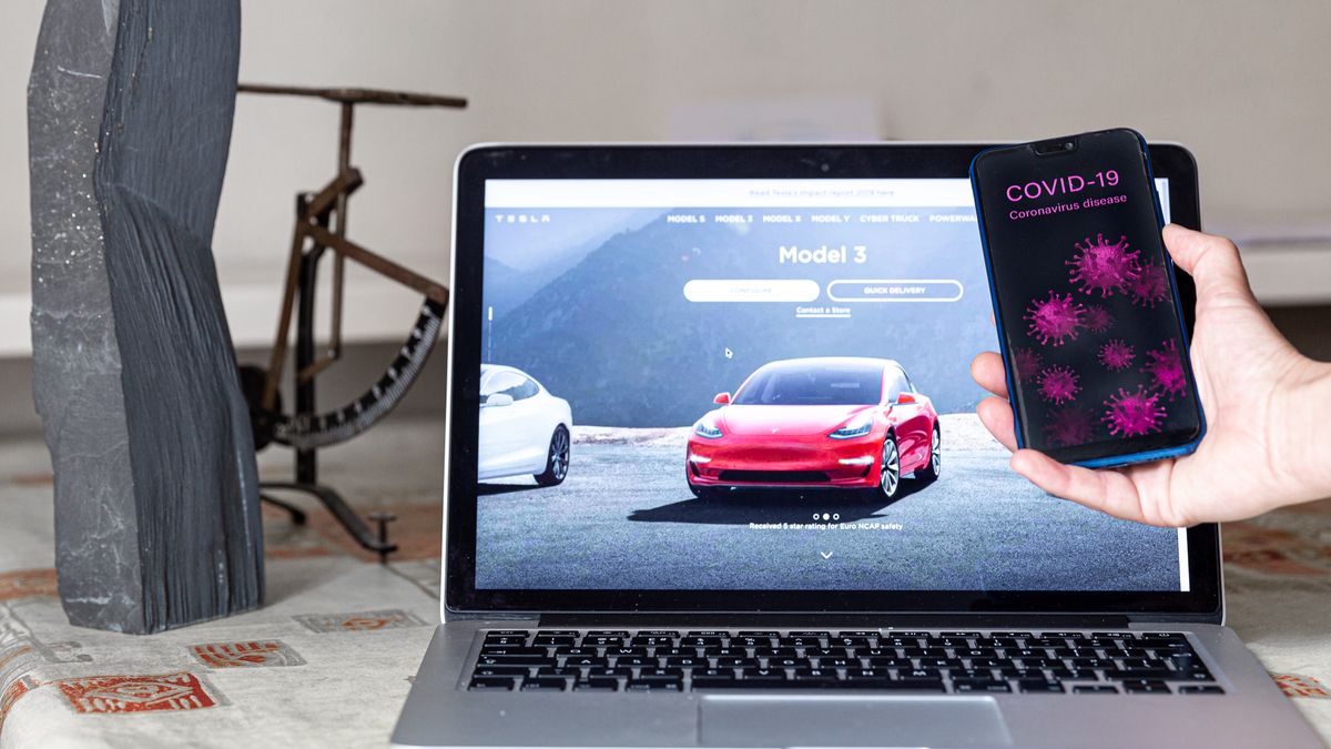 For illustrative purposes a woman holds a telephone with Covid-19 image in front of Tesla website as Tesla experiences an unexpected increase in sales and profits, despite the automobile industry in general going through major difficulties due to global spread of Coronavirus, London, England July 23, 2020. (Photo Illustration by Dominika Zarzycka/NurPhoto via Getty Images)