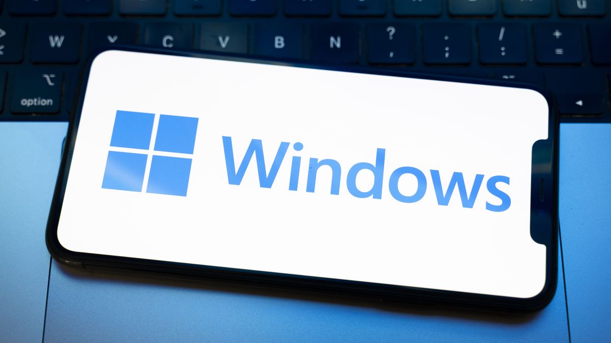 The Windows logo appears on the screen of a smartphone placed on a computer keyboard illuminated by blue and white light. Microsoft releases a major update to Windows 11 (25H2) and Windows 10 support ends permanently on October 14. In Creteil, France, on October 9, 2025. (Photo by Samuel Boivin/NurPhoto via Getty Images)