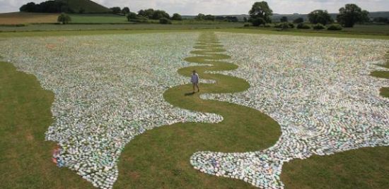 Artist Bruce Munro with his 600,000 CD art installation at Long Knoll, Wiltshire. See SWNS story SWCD: A innovative artist has created a glittering ocean 40 miles inland - using 600,000 recycled COMPACT DISCS. Renowned light installation artist Bruce Munro, 51, created the enormous CD wave to give a feeling of ''reflection'' using commonplace materials. He directed a team of 140 volunteers as they placed the myriad shiny discs in an intricate wave pattern on the grounds of his farmhouse in Kilmington, Wilts., to create 'CD Sea'. The reflective discs are consistently laid out over 10,000 square metres of grass, interrupted only by a single serpentine wave of grass running across the field. Father-of-four Bruce said: ''Lots of the pieces that I work on are about reflection - about what might be and what has gone before.