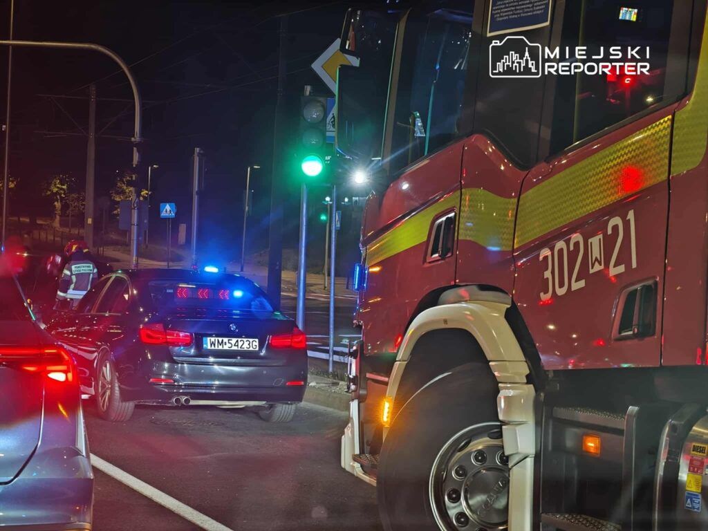 Kierowca samochodu osobowego z policyjnymi sygnalizatorami zatrzymany przy zielonym świetle, obok stoi wóz strażacki.