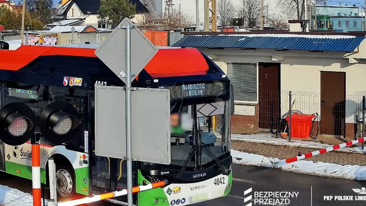 Autobus komunikacji miejskiej pomiędzy rogatkami na przejeździe kolejowym w Świdniku