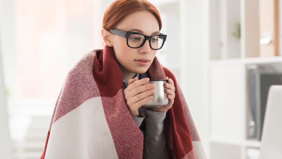 Winter in officeYoung woman in plaid and eyeglasses drinking hot tea from mug during work in officebusiness, 1 woman, one woman, person, young, adult, corporate, executive, professional, profession, manager, economist, accountant, employee, job, contemporary, woman, businesswoman, office, eyeglasses, staff, specialist, cold, freezy, Caucasian, workplace, networking, browsing, e-business, wi-fi, mobile, technology, communication, laptop, drink, warm-up, warm, hot, tea, mug, student, remote, winter, plaid, wrapped, video-chat, thesis, webinar, webcast