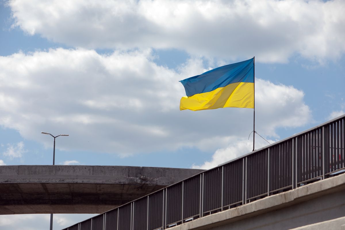 KYIV REGION, UKRAINE - MAY 23, 2022 - The national flag of Ukraine is seen at the reconstruction site in the village of Stoyanka where work continues to restore the bridge over the Irpin River that was destroyed on February 25 to stop the russian army's offensive, Stoyanka village, Bucha district, Kyiv Region, northcentral Ukraine. This photo cannot be distributed in the russian federation. (Photo credit should read Yevhen Lyubimov/ Ukrinform/Future Publishing via Getty Images)