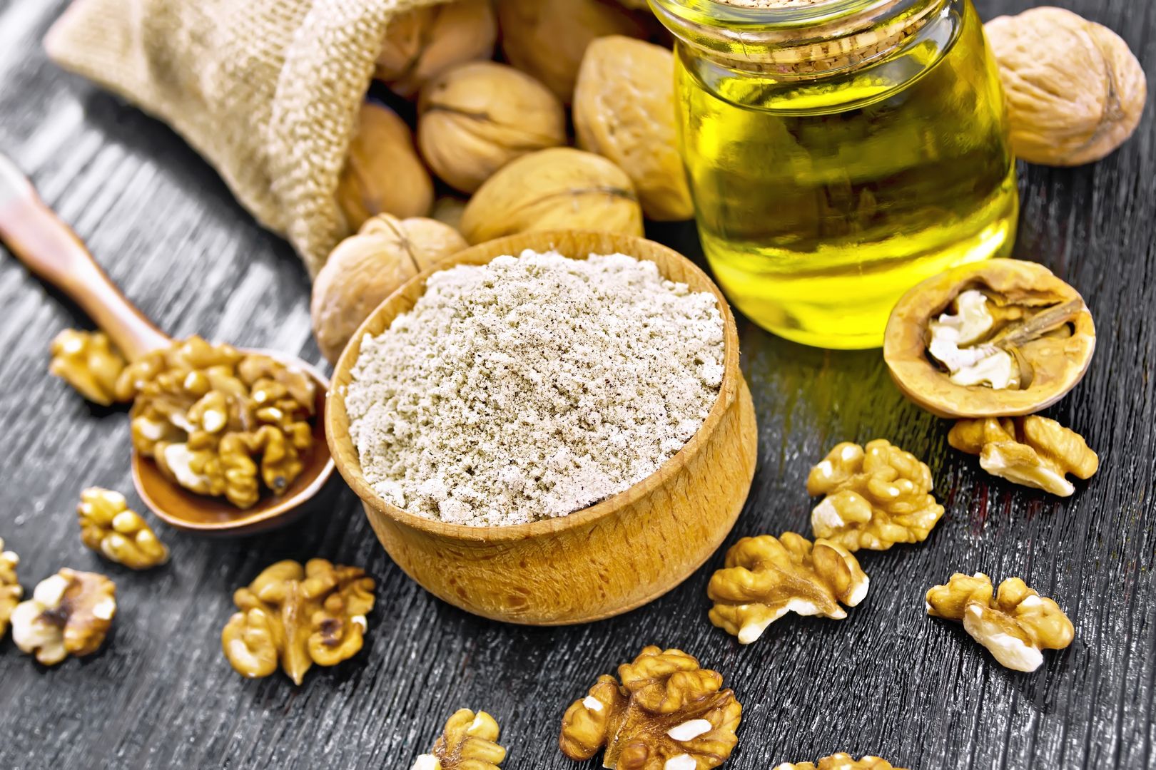 Walnut flour in bowl, nuts on a table, in a spoon and in a bag, oil in glass jar on black wooden board backgroundkostrezflour, oil, seed, walnut, core, oilplant, nut, food, kernel, spoon, bowl, nutrition, jar, glass, ingredient, baking, nature, eating, culinary, meal, diet, fruit, peeled, healthy, snack, plant, freshness, cooking, vegetarian, calorie, energy, organic, protein, dry, vitamin, natural, fresh, nutshell, whole, shell, bag, burlap, wooden, table, crop, board, horizontal, nobody, indoors, color