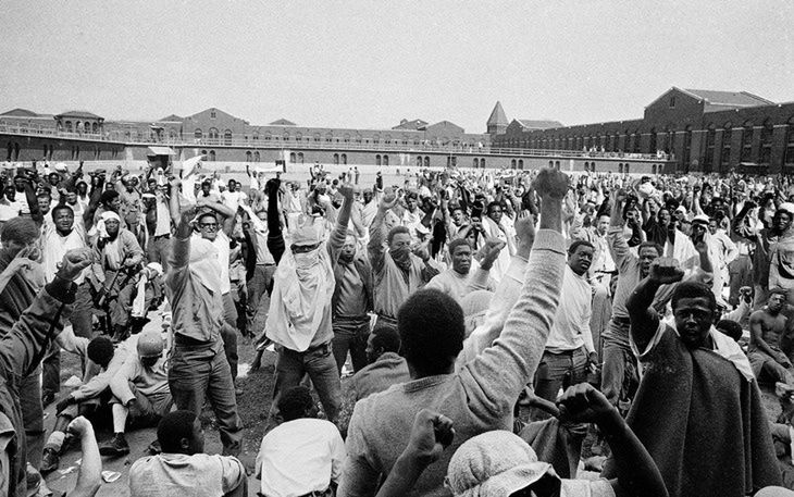 Więźniowie na dziedzińcu D, w bojowych nastrojach, wznoszą pięści w geście ruchu Black Power;
10 września. (Dzięki uprzejmości Associated Press)
