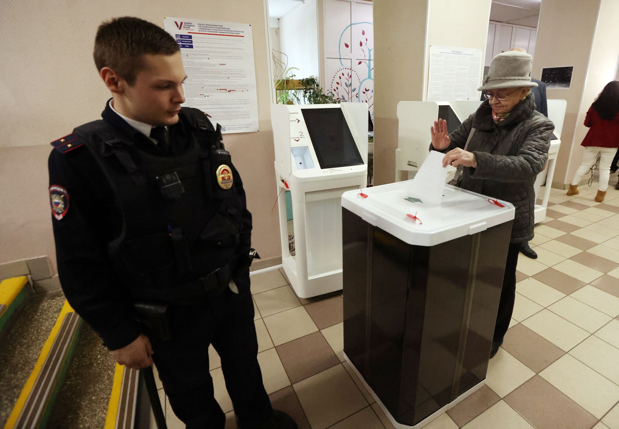 Russia Votes In  Presidential ElectionsMOSCOW, RUSSIA - MARCH 16: (RUSSIA OUT) A Russian Police officer (L) looks at a woman who casts her ballot while visiting the polling station during the second day of the Presidential Elections on March 16, 2024, in Moscow, Russia. Russian President Vladimir Putin is expected to win the 2024 Presidential Elections, planned for March 15-17. (Photo by Contributor/Getty Images)Contributor