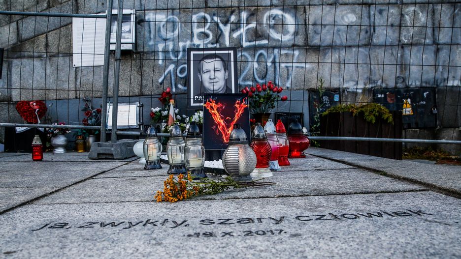 Znicze i kwiaty w miejscu samospalenia Piotra Szczęsnego w Warszawie