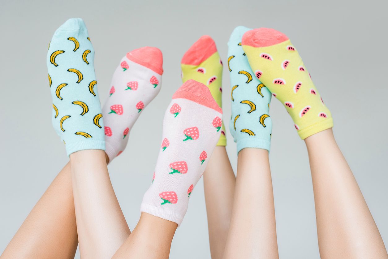partial view of female feet in colorful fruity socks, isolated on grey 
