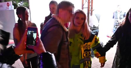 Margaret w kurtce robotnika i klapkach wytyka język w stronę paparazzi
