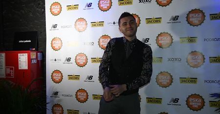 Elegancki Kamil Bednarek zaciska dłonie na ściance