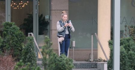 Małgorzata Socha wpatruje się w telefon pod kliniką medycyny estetycznej