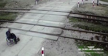 Mężczyzna na wózku przekracza tory