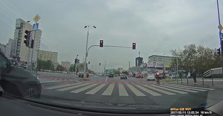 Rowerzysta przejeżdża przez ruchliwe skrzyżowanie na czerwonym świetle