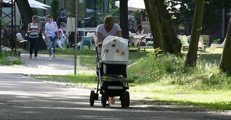 Zrezygnowana Zielińska pcha wózek w parku
