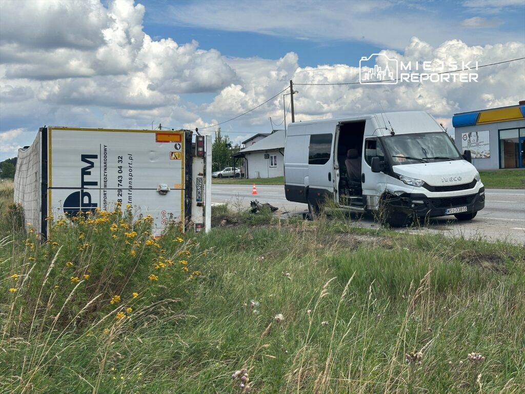 Przewrócona ciężarówka z widocznym napisem "PTM" oraz uszkodzony furgon marki Iveco na poboczu drogi.