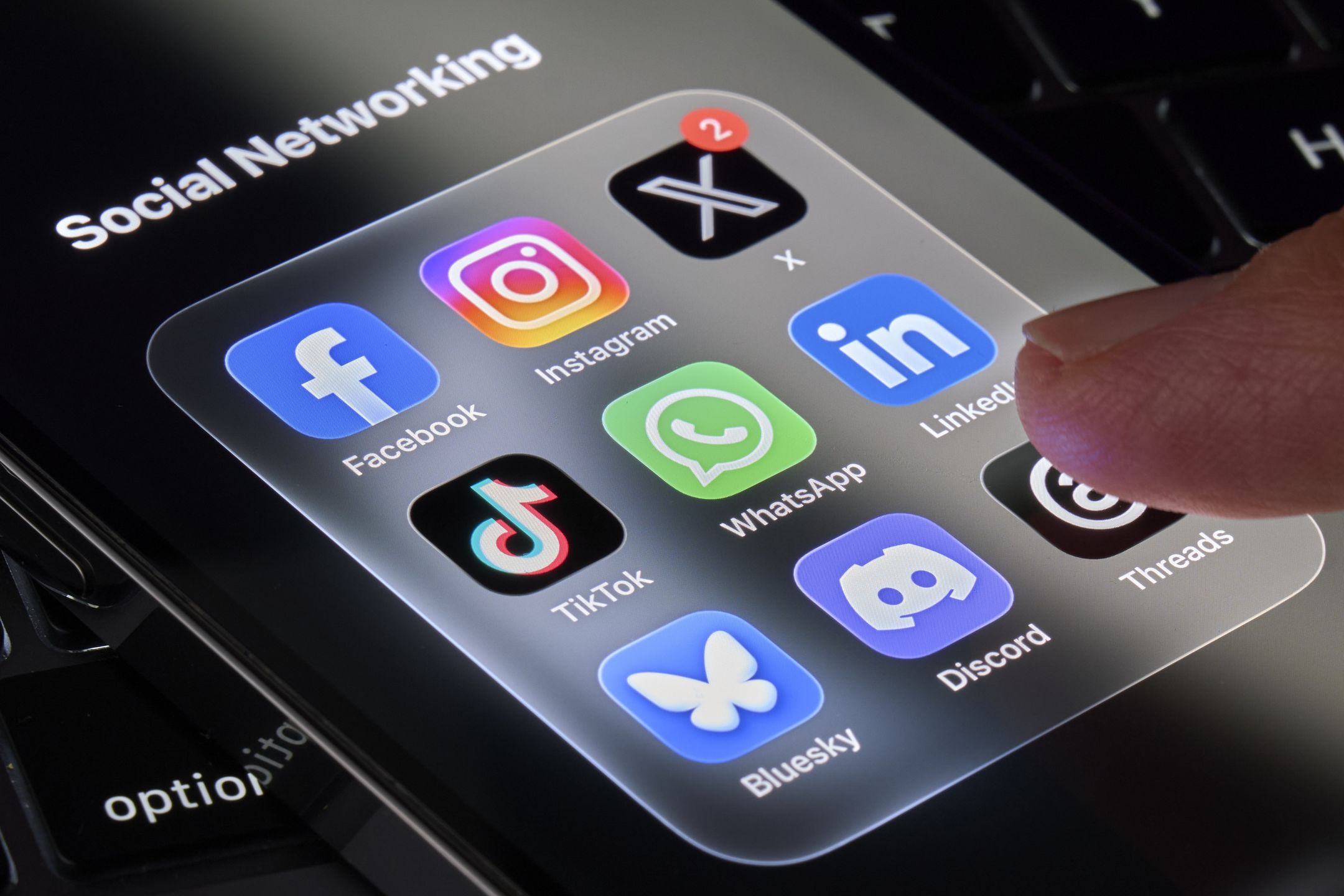 A hand is seen tapping on a smartphone screen displaying a Social Networking folder with icons for Facebook, Instagram, X, LinkedIn, WhatsApp, TikTok, Discord, Threads and Bluesky in this illustration photo taken on July 11, 2026, in Milan, Italy. (Photo by Matteo Della Torre/NurPhoto via Getty Images)