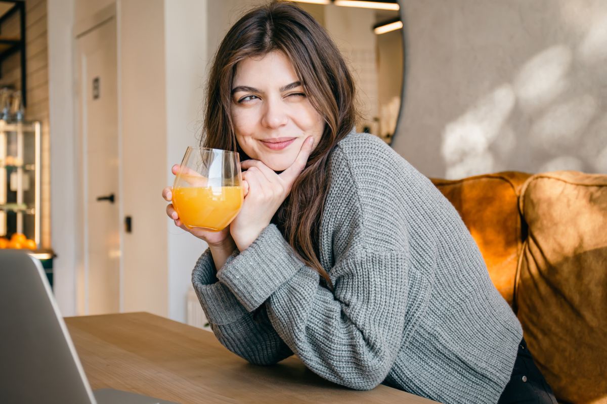 The woman is holding a glass of juice in her hands.