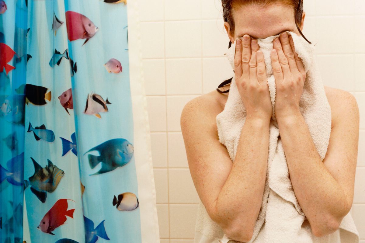 The woman is drying herself with a towel.