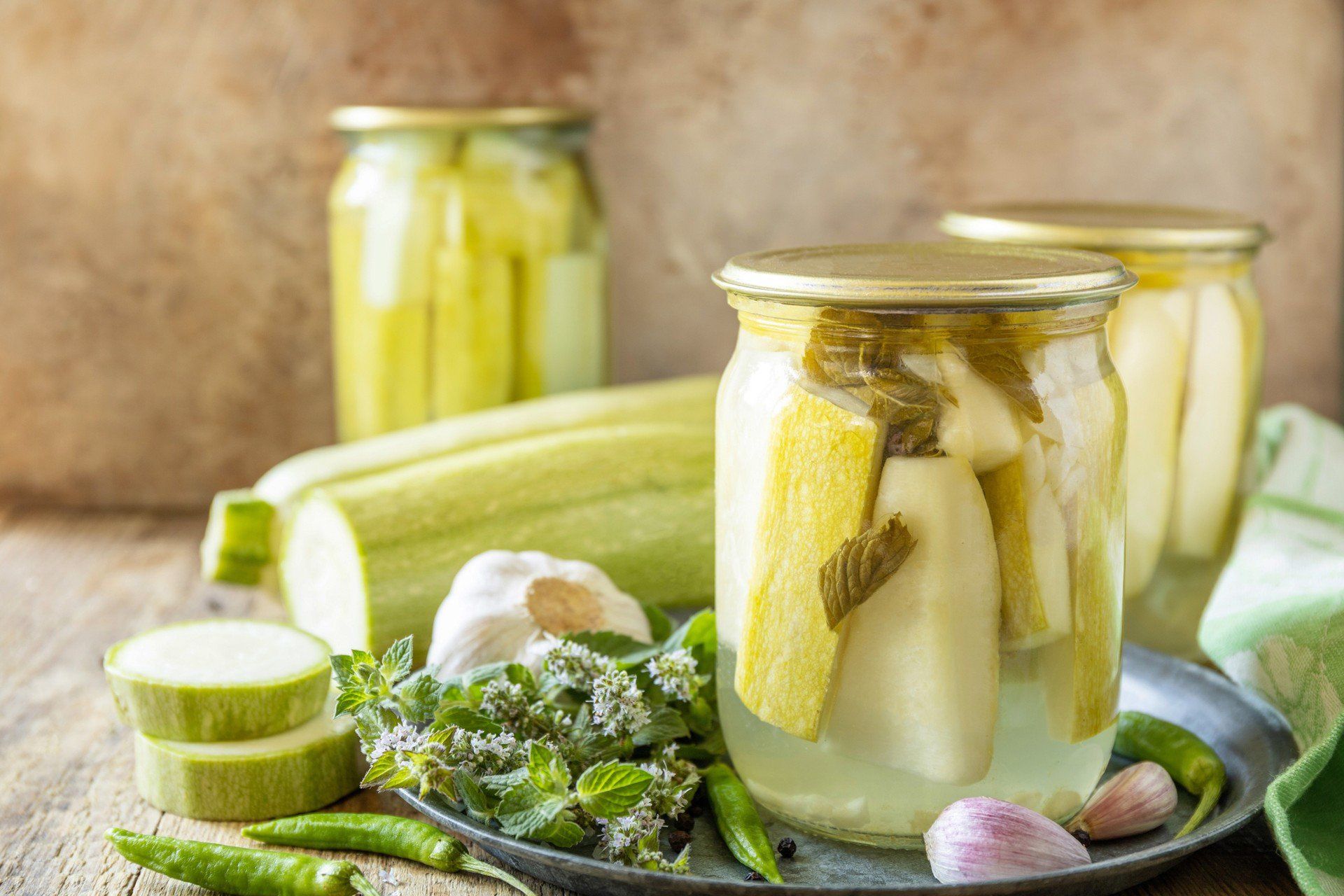 Healthy homemade fermented food. Pickled zucchini with mint preserved canned in glass jar. Home economics, autumn harvest preservation. Copy space.