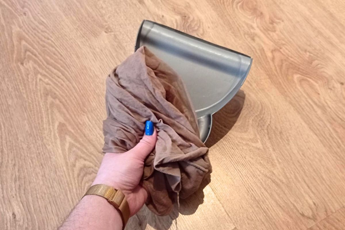 The woman holds a dustpan and pantyhose.