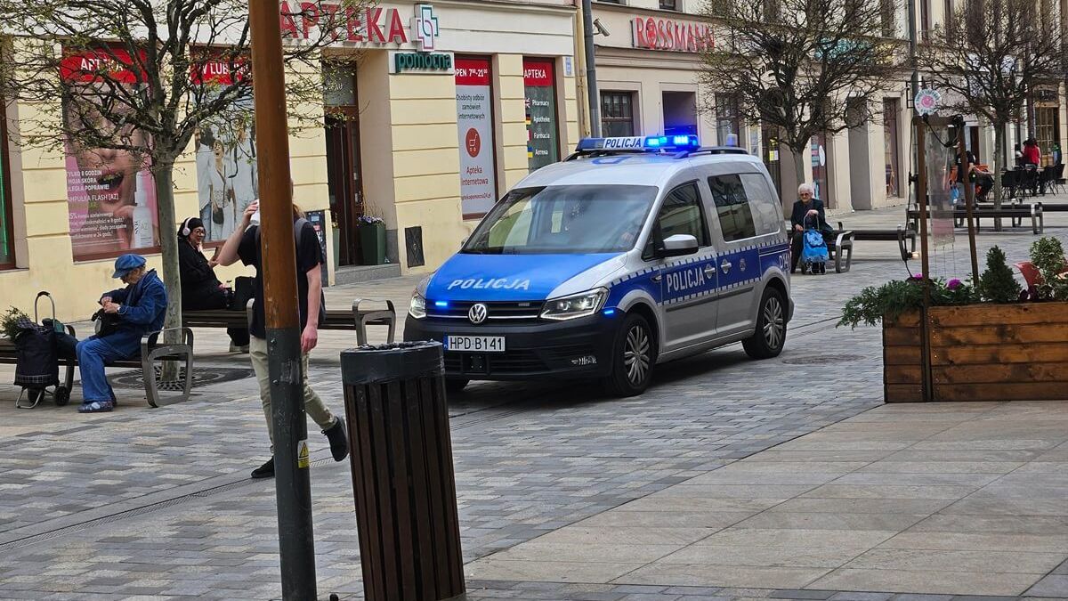 Policyjny radiowóz na sygnale jadący deptakiem