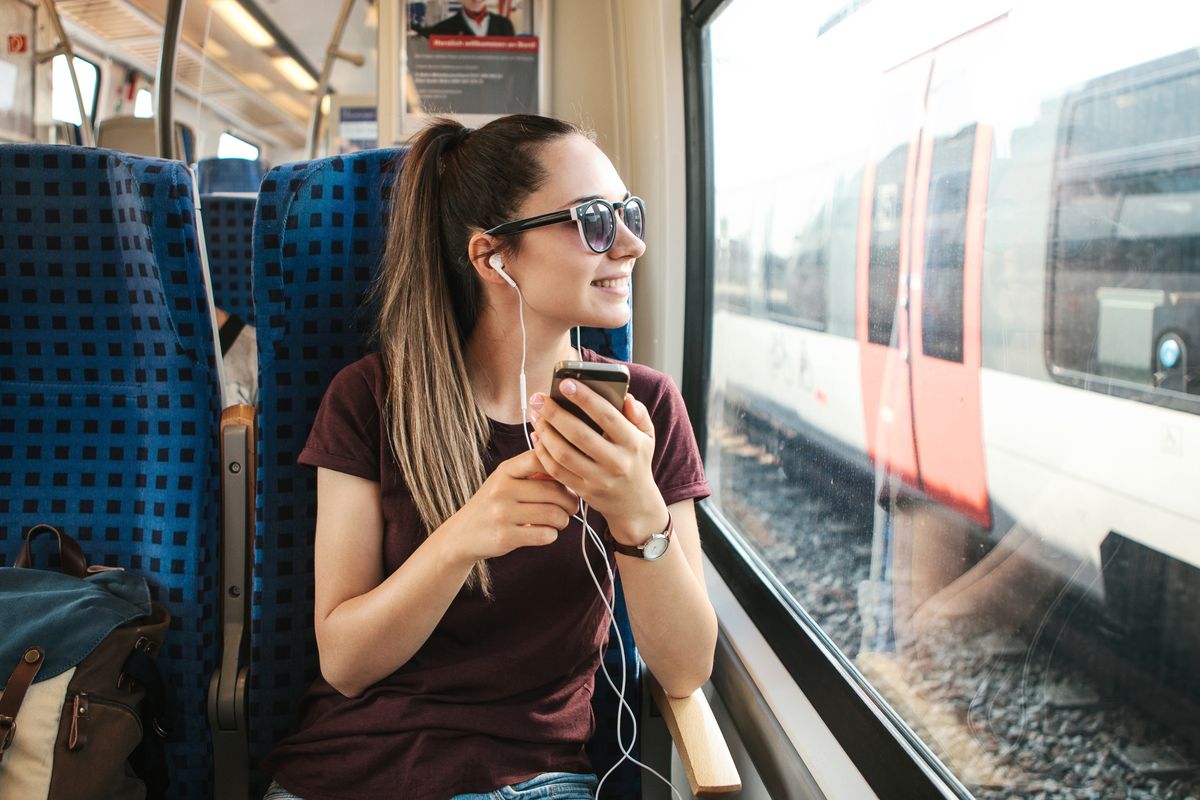 A young girl listens to a music or podcast while traveling in a train
