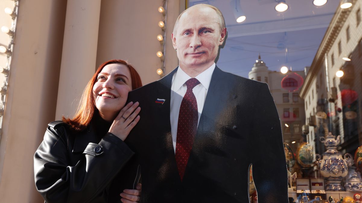 MOSCOW, RUSSIA - MARCH 14: (RUSSIA OUT) A woman poses for a photo beside a full-length cardboard cut-out of President Vladimir Putin at a souvenir shop ahead of the upcoming elections for the President of Russia on March 14, 2024 in Moscow, Russia. Russian President Vladimir Putin is expected to win the 2024 Presidential Elections, planned on March 15-17. (Photo by Contributor/Getty Images)