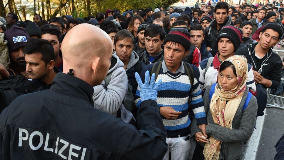 Niemiecki policjant rozmawia z imigrantami. Zdjęcie ilustracyjne