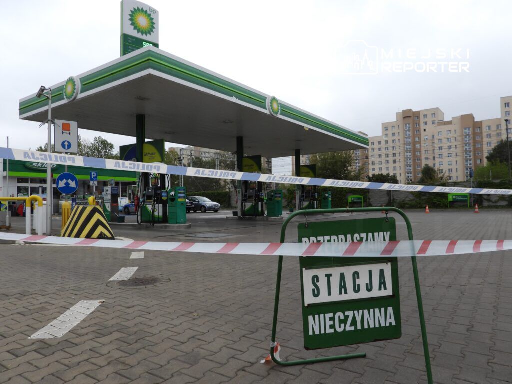 Stacja benzynowa z zamkniętymi dystrybutorami, ogrodzona taśmą policyjną, z tablicą "STACJA NIECZYNNA".