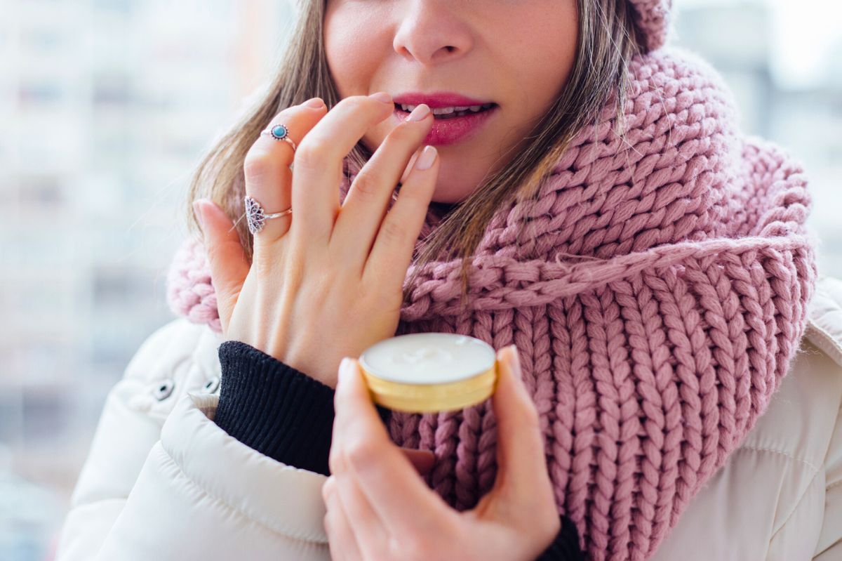 The woman is applying cosmetics to her lips.