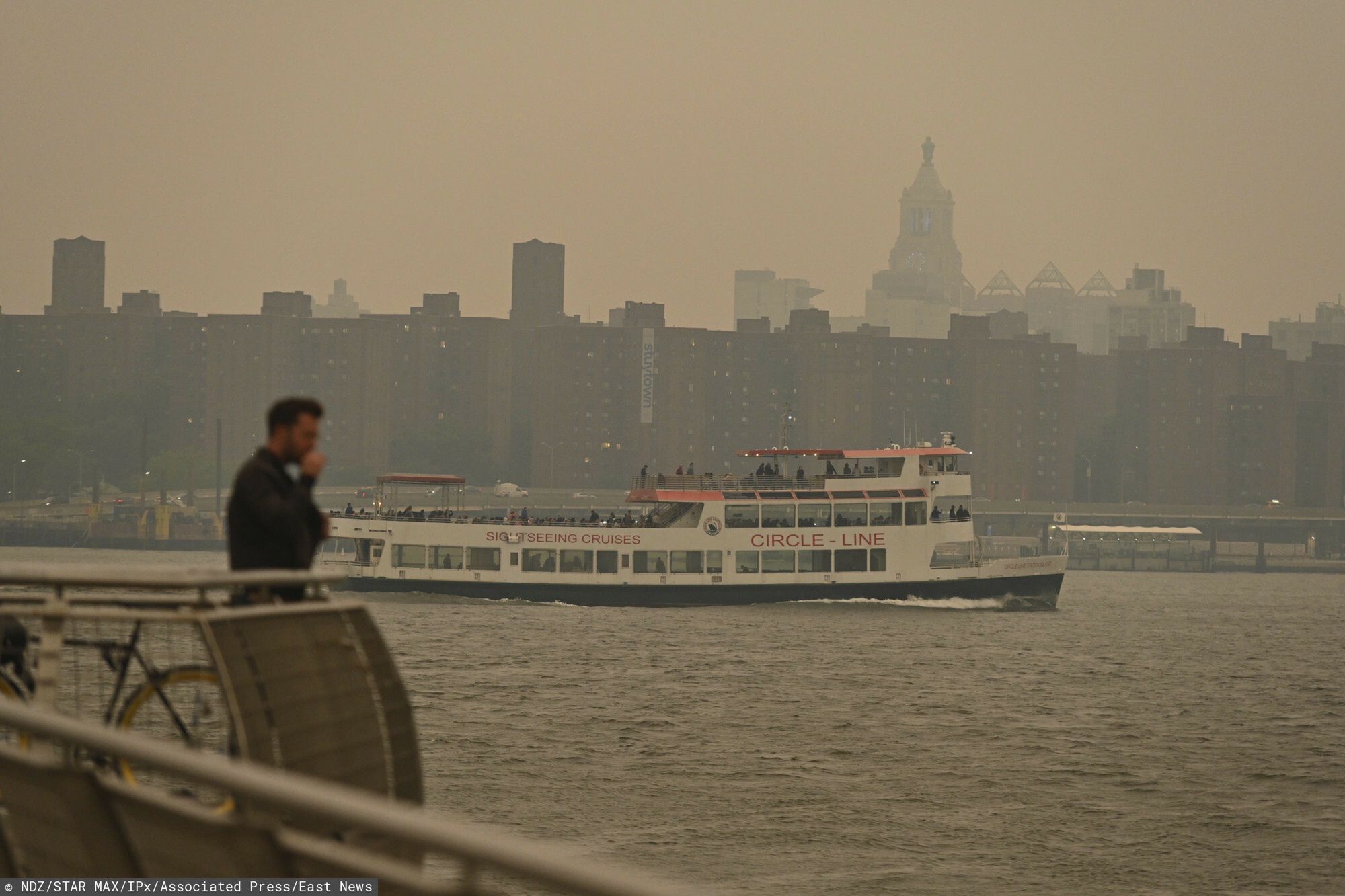Prom Circle Line przepływa obok mostu Williamsburg, gdy panoramę Manhattanu spowija dym z pożarów w Kanadzie, 6 czerwca 2023 r. w Nowym Jorku.