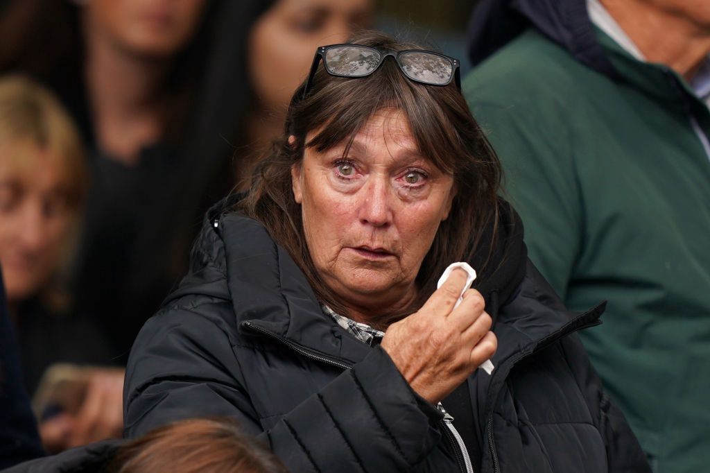 The State Funeral Of Queen Elizabeth IILONDON, ENGLAND - SEPTEMBER 19: A tearful mourner wipes their eyes during the State Funeral of Queen Elizabeth II on September 19, 2022 in London, England. Elizabeth Alexandra Mary Windsor was born in Bruton Street, Mayfair, London on 21 April 1926. She married Prince Philip in 1947 and ascended the throne of the United Kingdom and Commonwealth on 6 February 1952 after the death of her Father, King George VI. Queen Elizabeth II died at Balmoral Castle in Scotland on September 8, 2022, and is succeeded by her eldest son, King Charles III.  (Photo by Peter Summers/Getty Images)Peter Summers