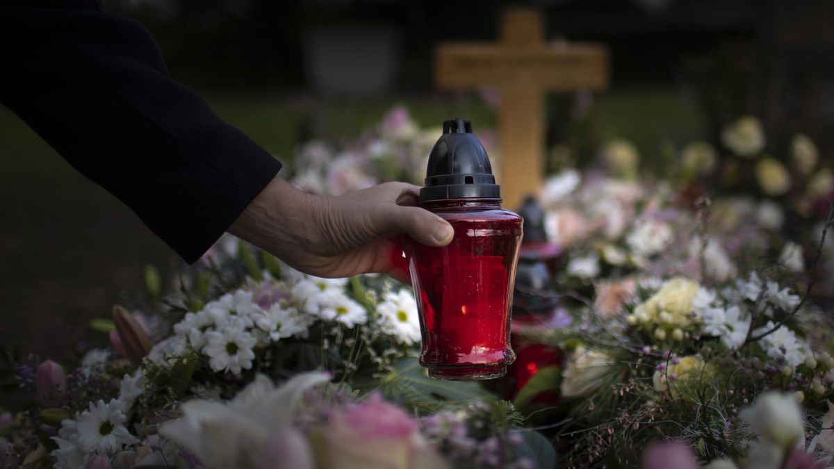 Cemetery, farewell,Bonn, Germany - January 21:  In this photo illustration a man puts a grave light on a grave on January 21, 2021 in Bonn, Germany. (Photo by Ute Grabowsky/Photothek via Getty Images)Ute Grabowskysymbolfoto, symbolbild, symbol picture symbol image, symbole, symbolisch, symbols, symbolic, creative, featurethemen, gesundheit, health, medizin, corona, uebersteblichkeit, friedhof, friedhoefe, cemeteries, christentum, abschied, sterben, tod, grab, begraebnis, trauer, trauern, grablicht, grablampe, grableuchte, kerze, blumen, kreuz, farewell, dying, burial, grieving, supernatural, grave light, grave lamp, flowers, cross