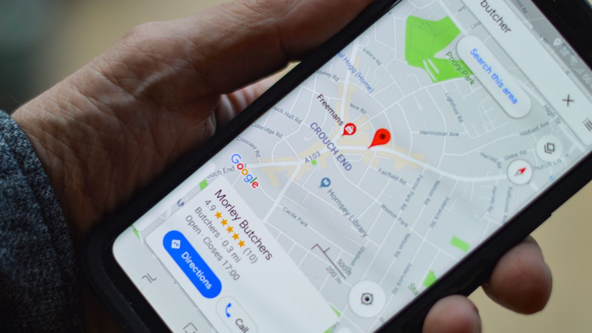 Męska ręka trzymająca smartfon z włączonymi Mapami Google