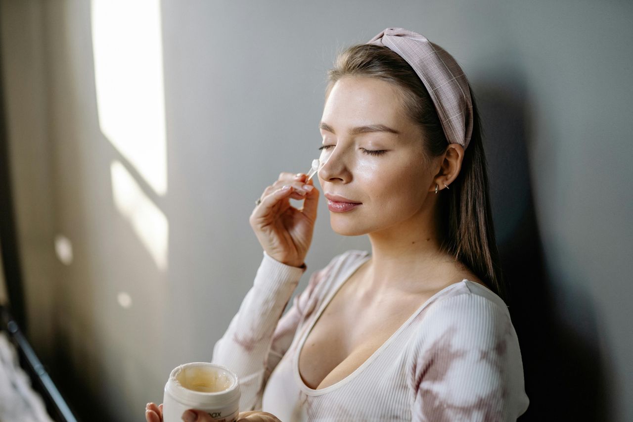 The woman is applying cream to her face.