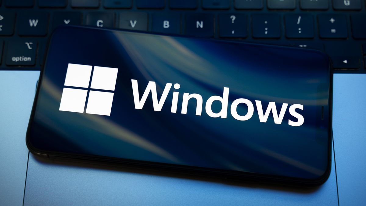 The Windows logo appears on the screen of a smartphone placed on a computer keyboard illuminated by blue and white light. Microsoft releases a major update to Windows 11 (25H2) and Windows 10 support ends permanently on October 14. In Creteil, France, on October 9, 2025. (Photo by Samuel Boivin/NurPhoto via Getty Images)