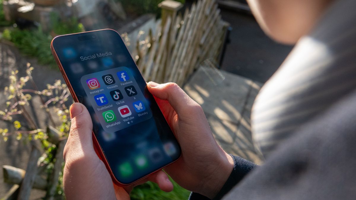 BATH, UNITED KINGDOM - MARCH 29: In this photo illustration a 14-year-old boy holds an iPhone screen displaying various social media and messaging apps on March 29, 2026 in Bath, England. On top row left to right, the logo of social media platform Instagram is seen beside that of Meta’s Threads and Facebook. On the middle row from left is the logo of Donald Trump's Truth Social app, next to the logo of social media app TikTok and the logo of Elon Musk’s US online social media and social networking site 'X' (formerly known as Twitter). Along the bottom row, left to right is the messaging service WhatsApp, the logo for online video sharing and social media platform YouTube and the logo for the Bluesky app. In the UK, a ban on social media for under-16s has been backed by the House of Lords following the Australian law which aims to stop children under 16 from having social media accounts and social media platforms, including TikTok, Facebook, Snapchat, Reddit, X, formerly Twitter, and Instagram potentially being be fined for preventing children younger than 16 from having social media accounts. (Photo by Anna Barclay/Getty Images)