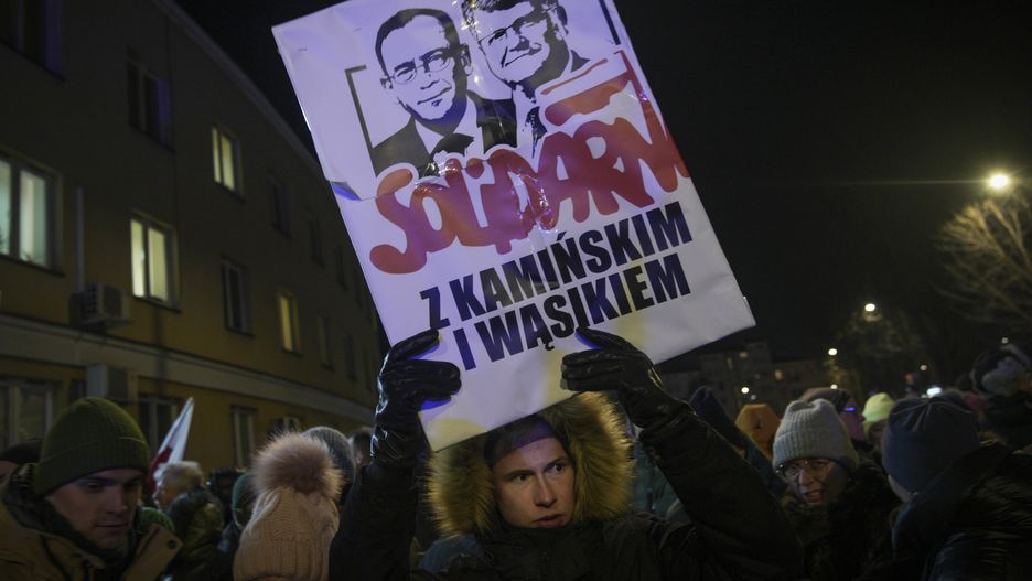 A protester holds a sign with effigies of detained former MPs Mariusz Kaminski and Maciej Wasik near the Grochow police station in Warsaw, Poland on 09 January, 2023. Scuffles between protesters and police erupted after supporters of two detained opposition MPs tried to breack into a police station. Maciej Wasik and Mariusz Kaminski on Tuesday were arrested on charges of abuse of power at the Presidential Palace where they sought refuge. (Photo by Jaap Arriens/NurPhoto via Getty Images)