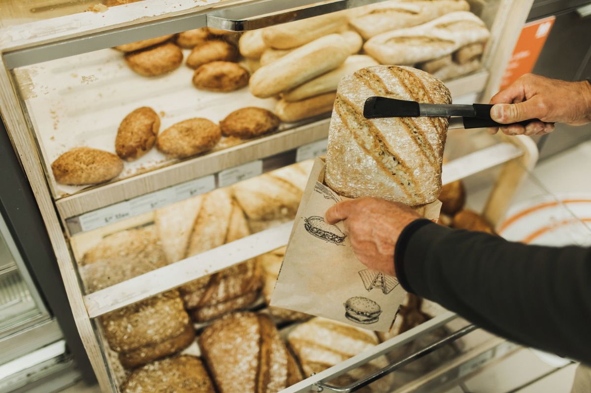 The man puts bread into the bag.