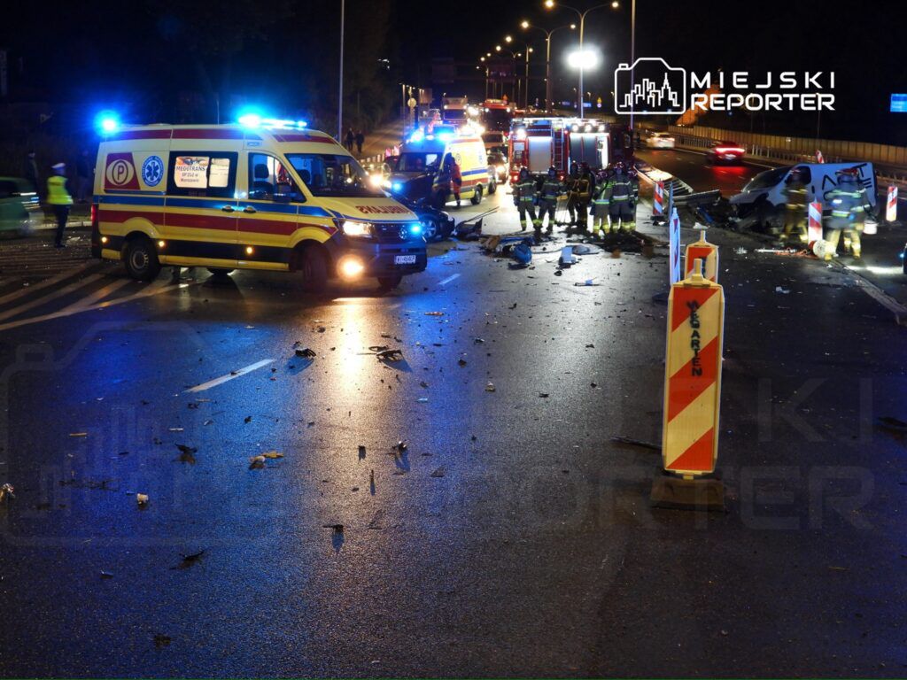 Służby ratunkowe pracują na miejscu wypadku, otaczając zniszczony pojazd na drodze w nocy.