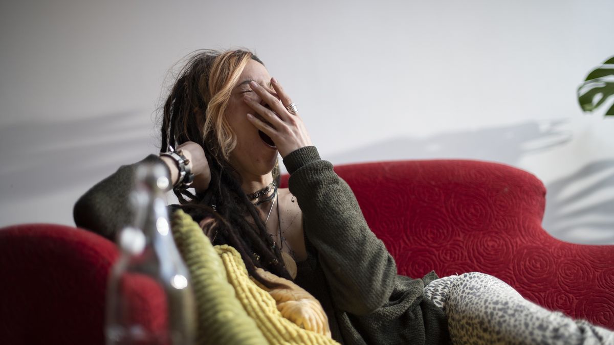 Young woman with a unique style, yawning and relaxing on a red sofa
Lucy Lambriex