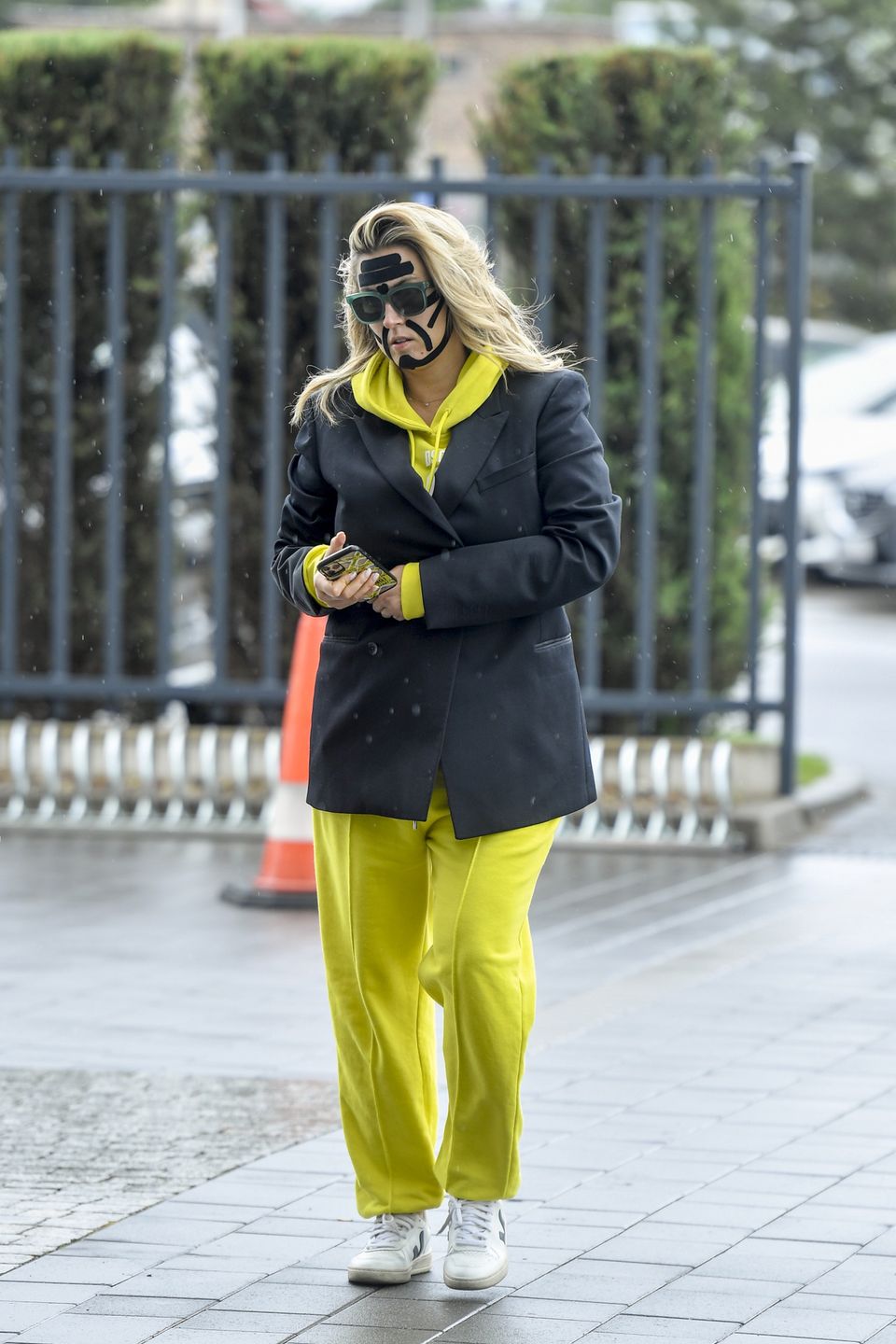 Karolina Szostak wpatrzona w telefon mknie do pracy z taśmami na twarzy 