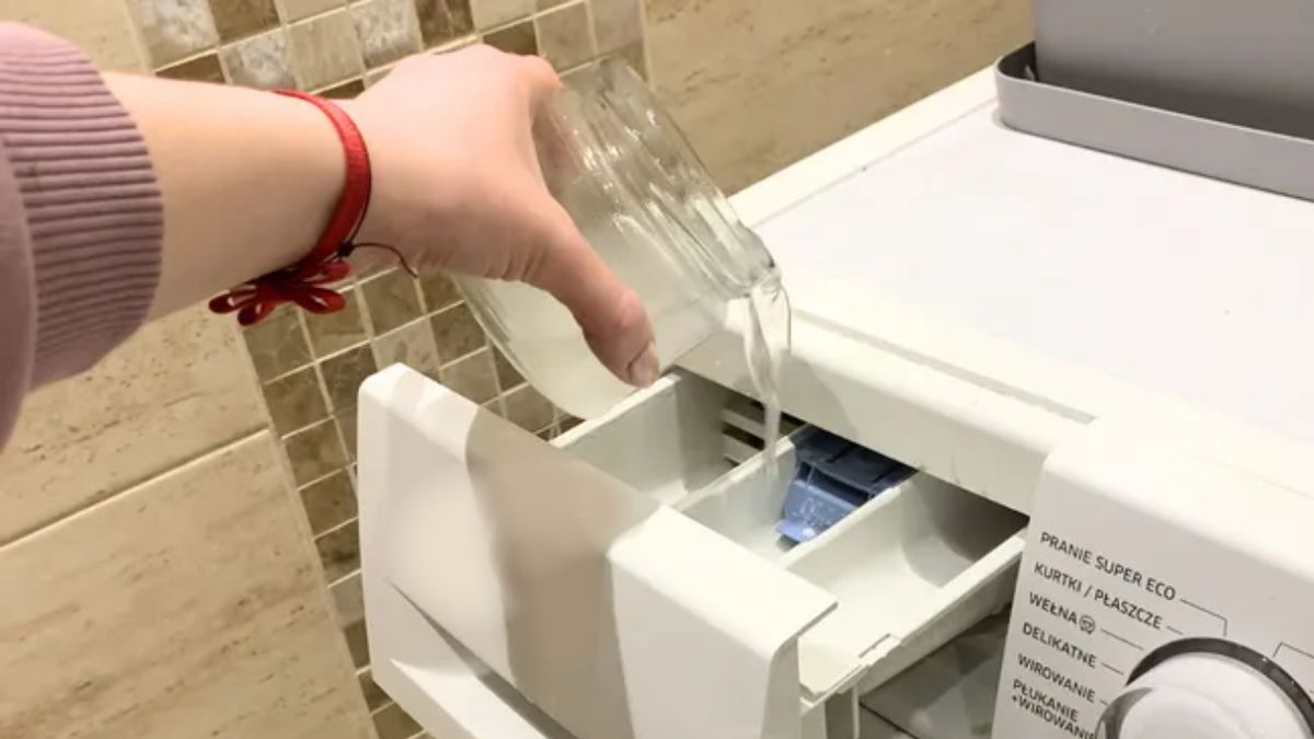 Kobieta wlewa płyn do szufladki w pralce