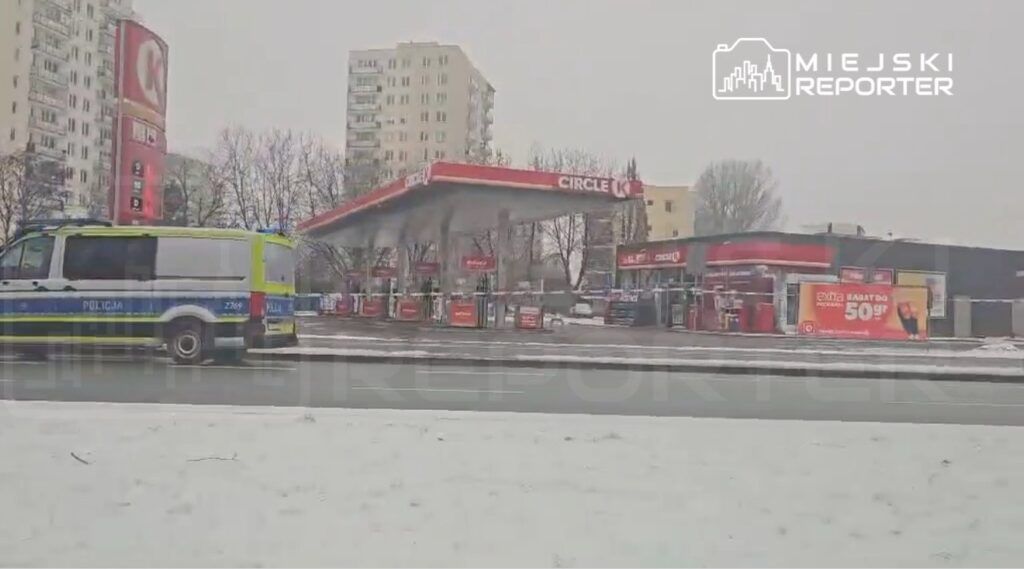 Policyjny radiowóz zaparkowany obok stacji benzynowej Circle K w zaśnieżonym otoczeniu miejskim.